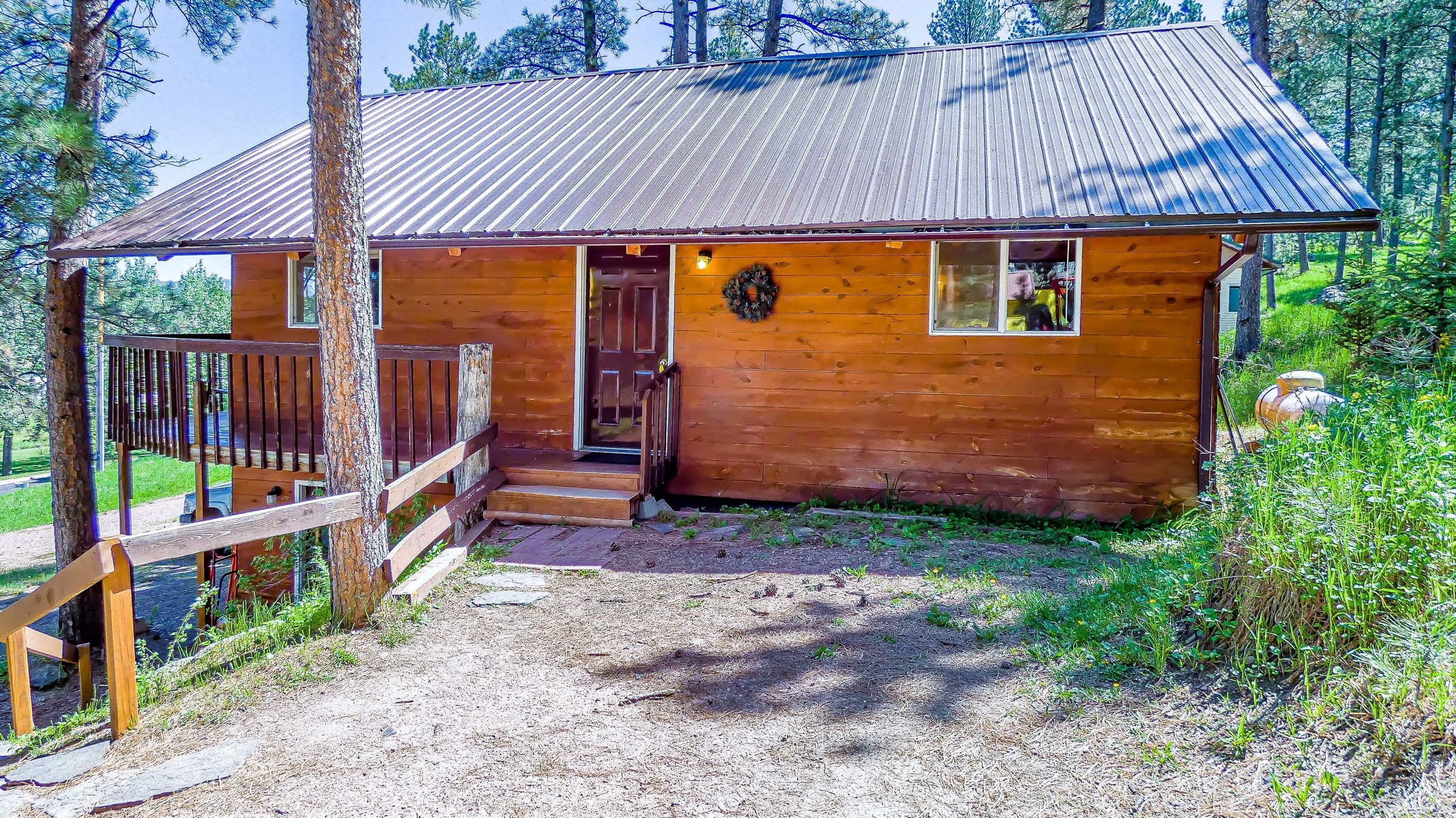 Cabin 13, the Hunting Lodge: wood-sided cabin with a metal roof and a wreath on the door